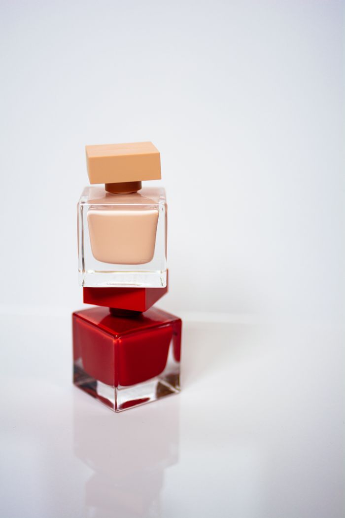 services-01 Close-up of luxury red and nude nail polish bottles stacked on a white background.