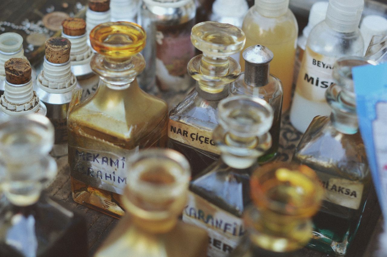 why-choose-us Collection of vintage glass perfume bottles with various labels in a close-up view.