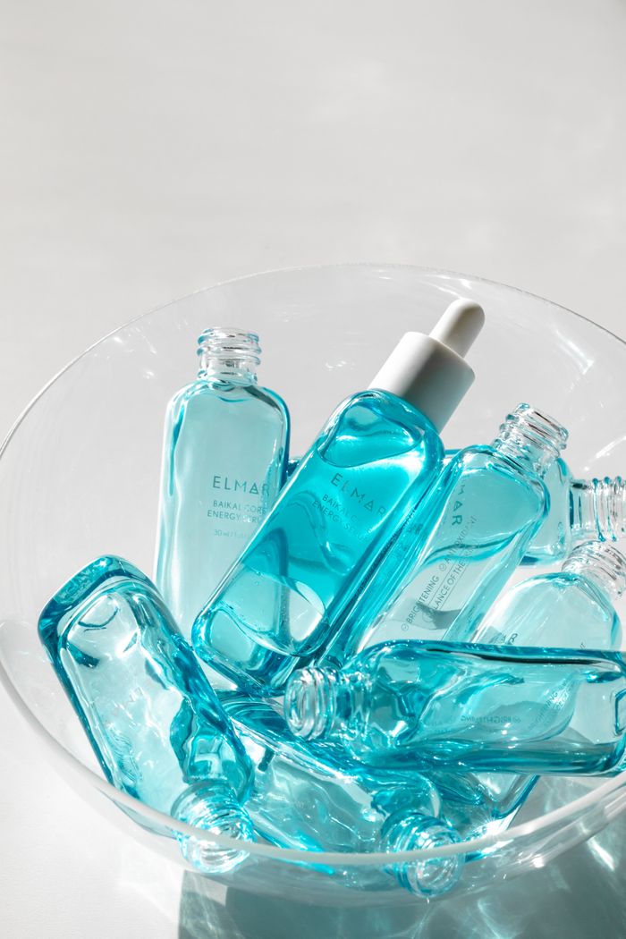 services-01 Sunlit clear glass bottles with blue liquid in a transparent bowl.