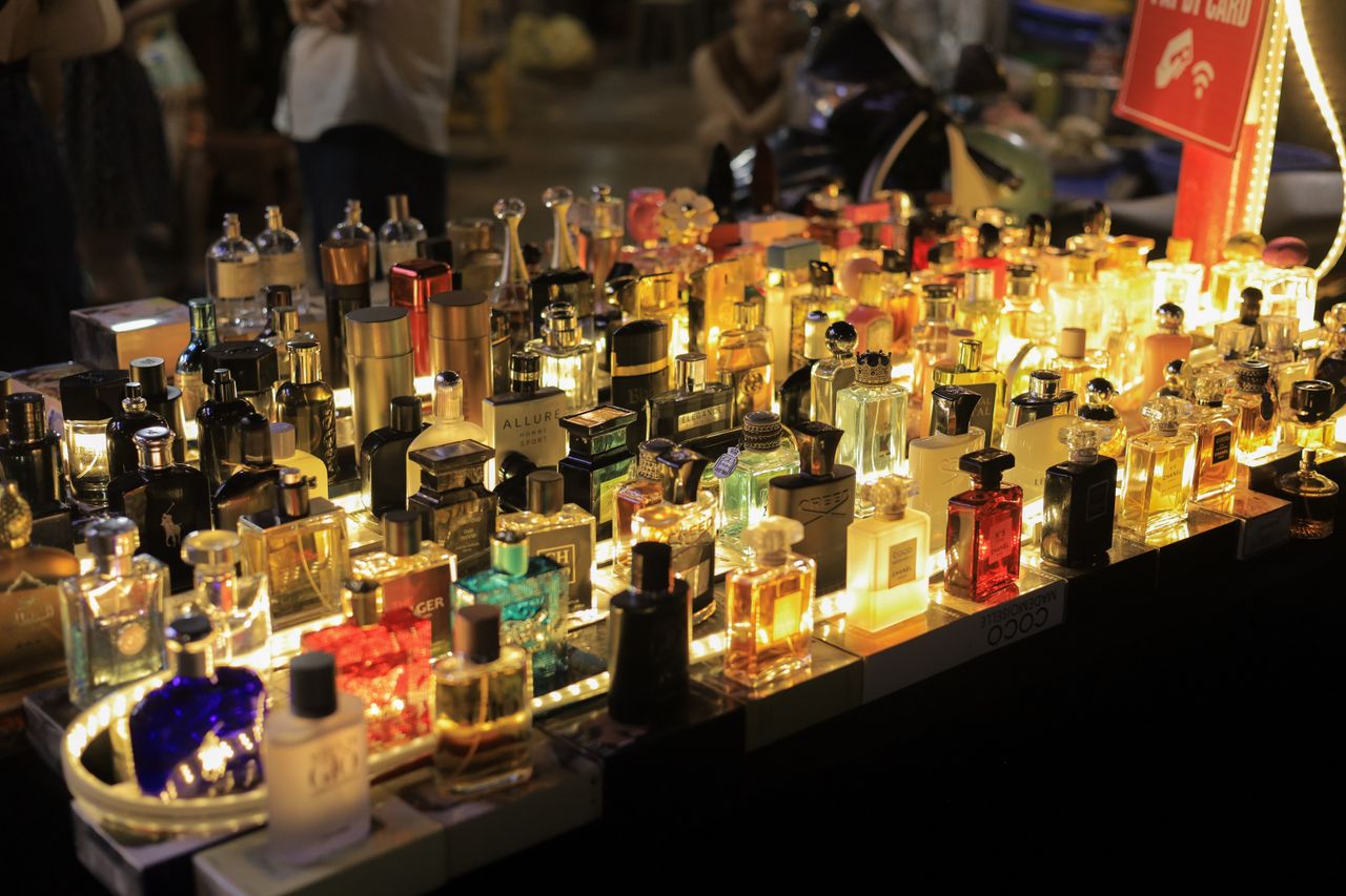 team-03 A colorful display of perfume bottles lit up at a night market in Vietnam, capturing the lively atmosphere.