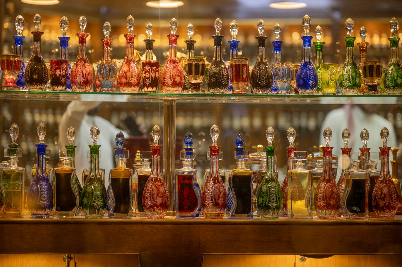team-04 Vibrant display of ornate glass bottles filled with assorted liquids on a shelf indoors.