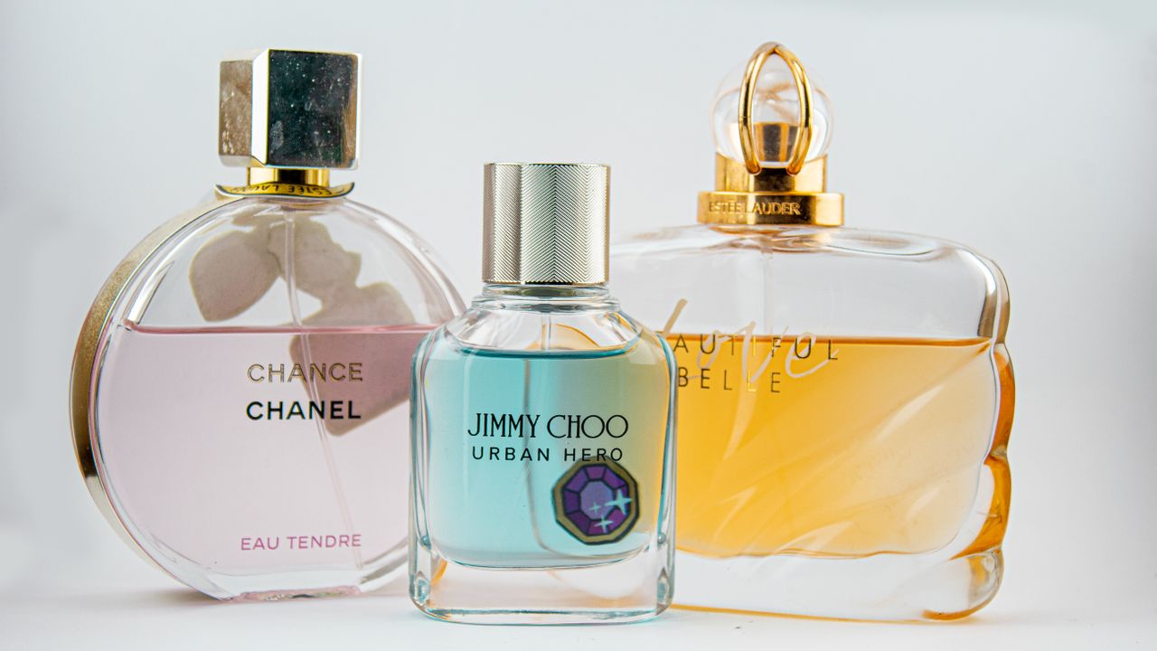 who-we-are Elegant display of designer perfume bottles featuring Chanel, Jimmy Choo, and Estee Lauder.