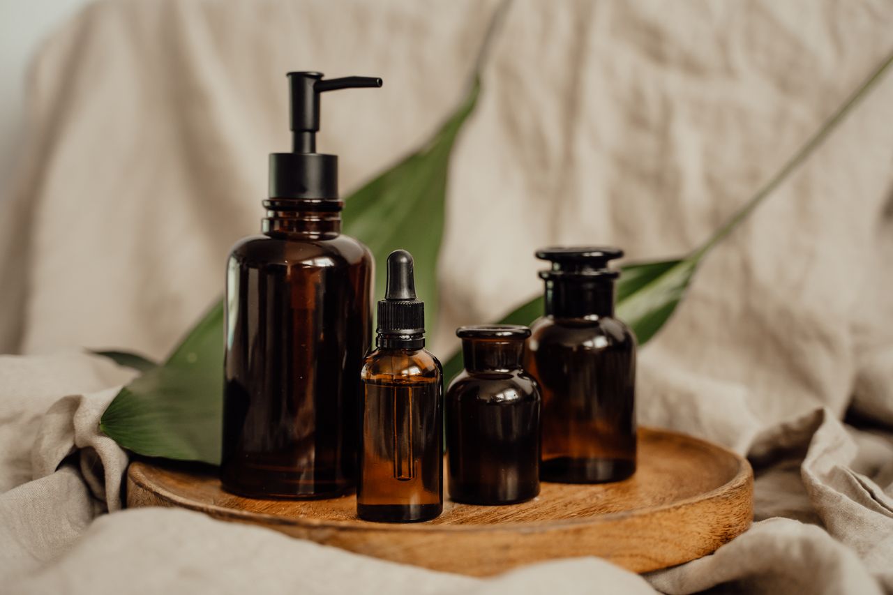 services-04 Stylish amber glass bottles arranged on a wooden tray with natural fabric background.