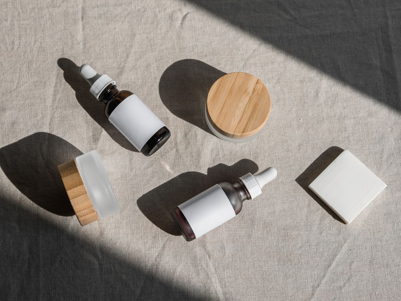 services-01 A minimalist flat lay of cosmetic bottles and jars on a linen cloth, perfect for beauty product presentations.